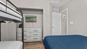 A bedroom with bunk beds, a dresser, a television, and a door.