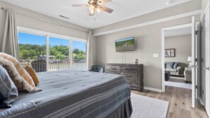 Un dormitorio con una cama grande, un aparador, un televisor y vistas a un lago desde la ventana.
