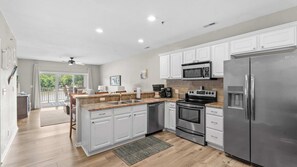 A modern kitchen with white cabinets, stainless steel appliances, and a large island with a sink.