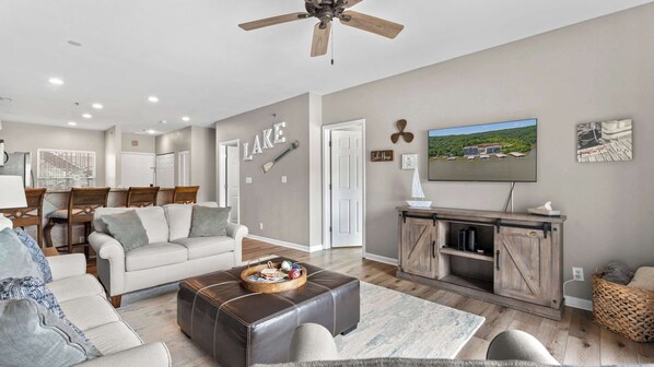 A modern living room with a sofa, ottoman, and a television on a wooden cabinet.