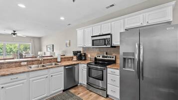 A modern kitchen with white cabinets, stainless steel appliances, and a granite countertop.