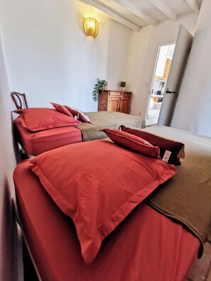 A room with two beds, a wooden cabinet, and a wall-mounted light fixture. - Mas en pierre, piscine et jardin privés, 2ch, 5 pers, 10min du Pont du Gard (Meynes)