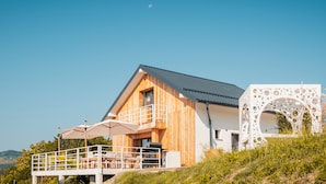 A modern wooden house with a balcony and a white decorative structure.