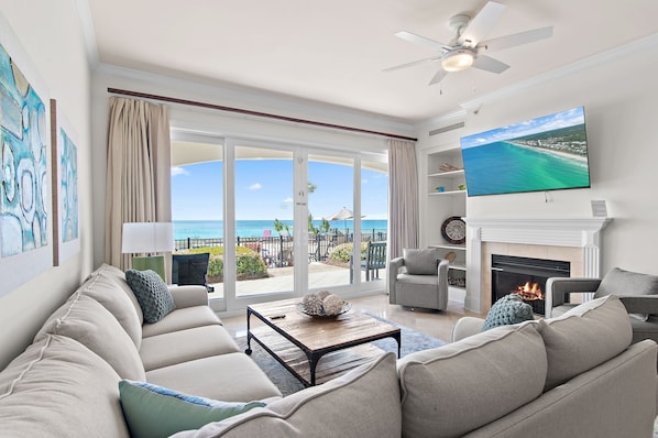 A living room with a sofa, a coffee table, a flat-screen TV, a fireplace, and a view of the ocean. - Adagio B103 | Beach Front |Bunk room | Private Beach |Resort Style Pool YFAB (Santa Rosa Beach)