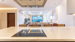 Een moderne keuken met een centraal kookeiland, inbouwapparatuur, hanglampen en uitzicht op de omgeving.