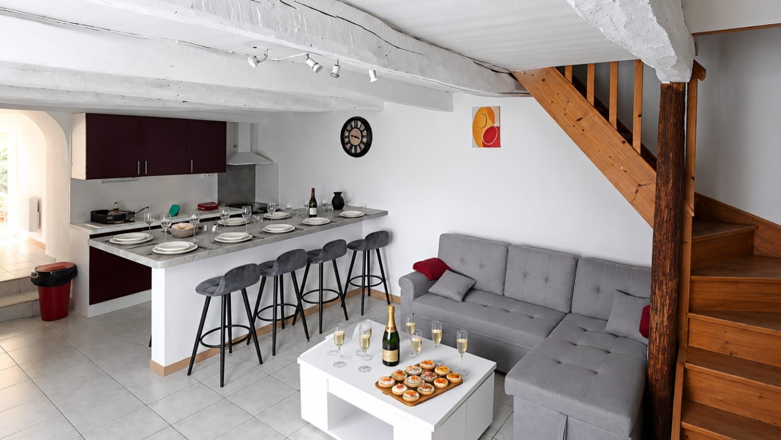 Een moderne keuken met een centraal eiland, barstoelen en een eettafel gedekt voor een maaltijd.