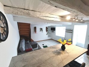 Una cocina moderna con encimera de mármol, televisor integrado y una escalera que sube a una zona tipo loft.