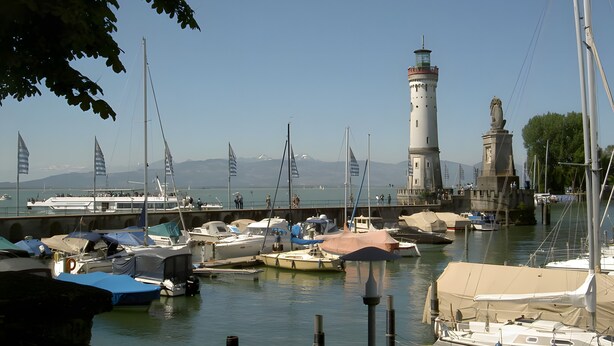 A marina with boats, a lighthouse, and a statue. - Holiday Apartment 'Dinkelbach Traumblick 3C' with Lake & Mountain View, Balcony, Wi-Fi (Wasserburg (Bodensee))