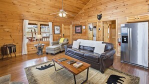 Ein Holzblockhaus-Innenraum mit einer Couch, einem Couchtisch und einem Kühlschrank.