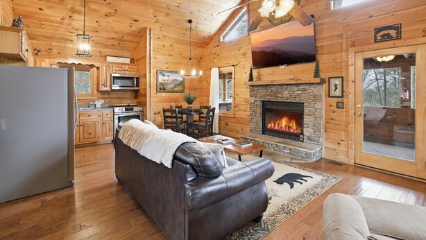 Ein Holzblockhaus-Interieur mit Kamin, Ledersofa, Essbereich, Küche und Holzwänden.