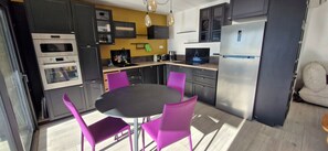 A modern kitchen with built-in appliances, a dining table with chairs, and a sofa in the adjacent living area. - BEAUSEJOUR SUD Front de Mer, 4-room apartment - Air-conditioned (Bandol)