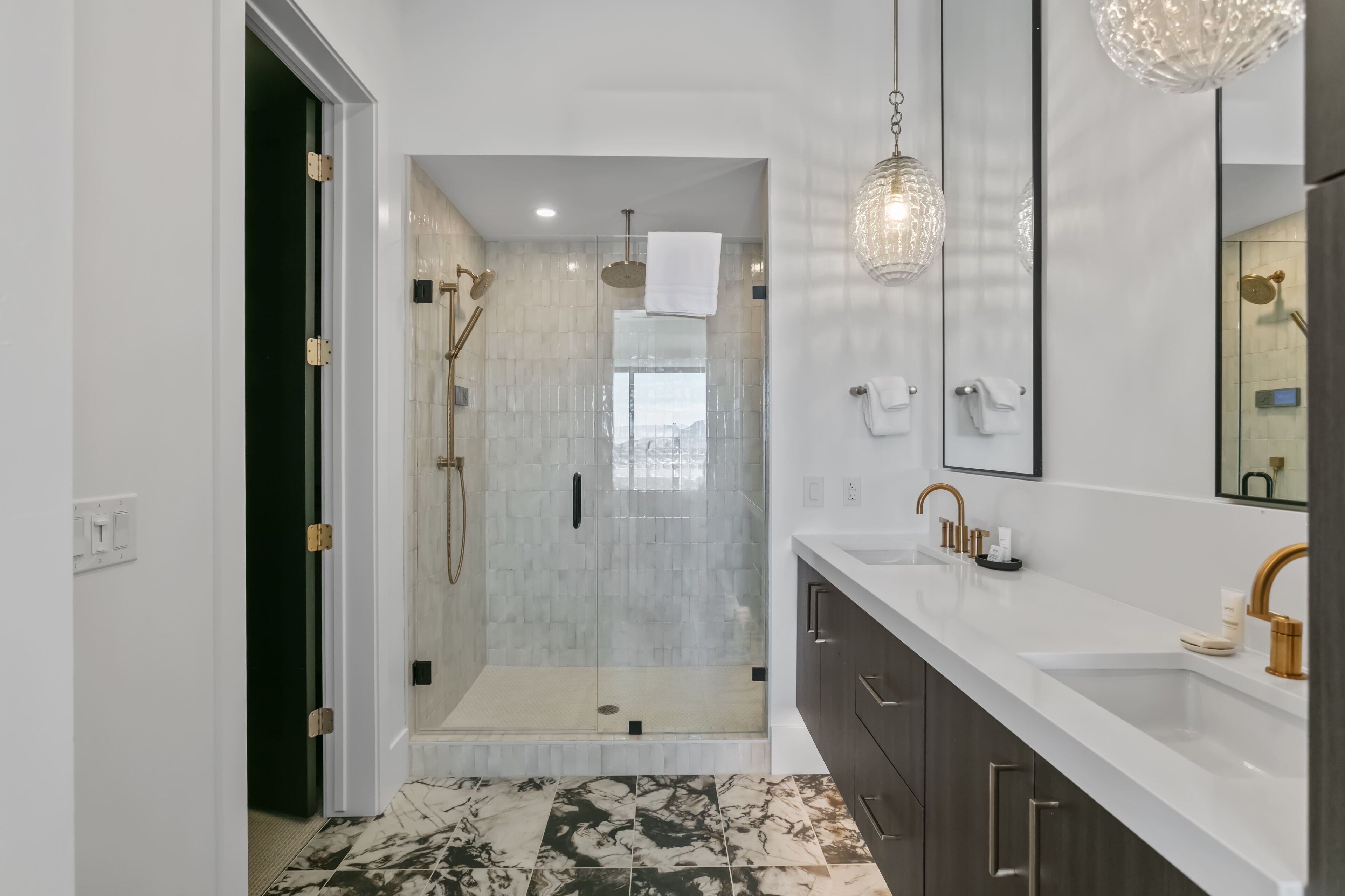 A modern bathroom with a walk-in shower, a large mirror, and a white countertop.