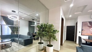 A modern interior with a glass partition, a seating area with a sofa and chairs, a potted plant, and a dining table. - Dara Resort  (Abuja)