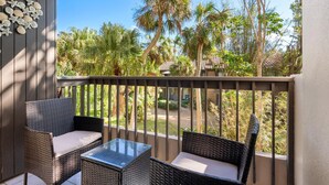 A balcony with wicker furniture and a view of palm trees and a building. - PRIVATE BEACH ACCESS, SPRING-FED LAKE, WALK TO SIESTA KEY VILLAGE! (Siesta Key)