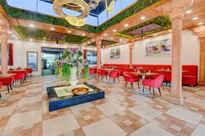 Tilava ravintola, jossa on korkeat katot, vihreät seinät ja punaiset istuimet.