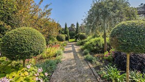 A garden pathway with neatly trimmed hedges and flowering plants. - Stunning English country house in rural Kent (Eastry)