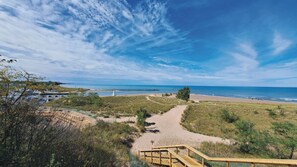 A beach with a wooden walkway leading to the shore, a lighthouse in the distance, and a clear blue sky. - Luxury retreat w/heated pool minutes to Downtown New Buffalo (New Buffalo)