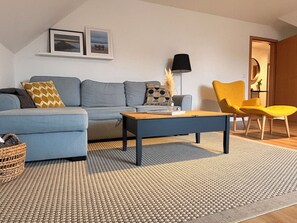Ein Wohnzimmer mit einer Couch, einem Couchtisch, einer Lampe und einem Sessel.