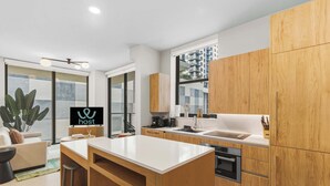 A modern kitchen with wooden cabinets, a central island, and a large window. - 2BR Suite | Rooftop Pool | Walk to Bayside (Miami)