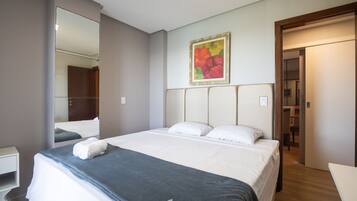 A hotel room with a large bed, a bedside table, a mirror, and a painting on the wall.