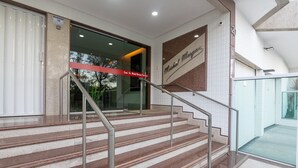 A set of marble stairs with metal railings leading to a glass door entrance. - Building w/ Pool in Front of the Beaches of Bacutia and Peracanga - Emqs (Guarapari)
