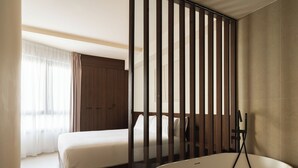Ein modernes Hotelzimmer mit einem großen Bett, einer Badewanne und einem Holzschrank.
