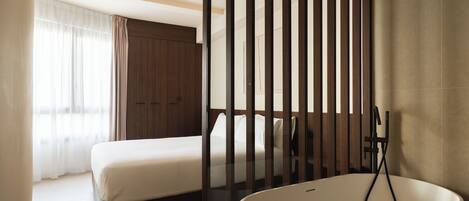 Una habitación de hotel moderna con una cama grande, una bañera y un armario de madera.
