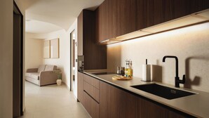 Eine moderne Küche mit einem dunklen Holzschrank, einem schwarzen Spülbecken und einer Arbeitsplatte mit einer Flasche und einem Papiertuchhalter.