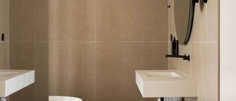 A modern bathroom with a freestanding bathtub, two sinks, a mirror, and a towel rack.