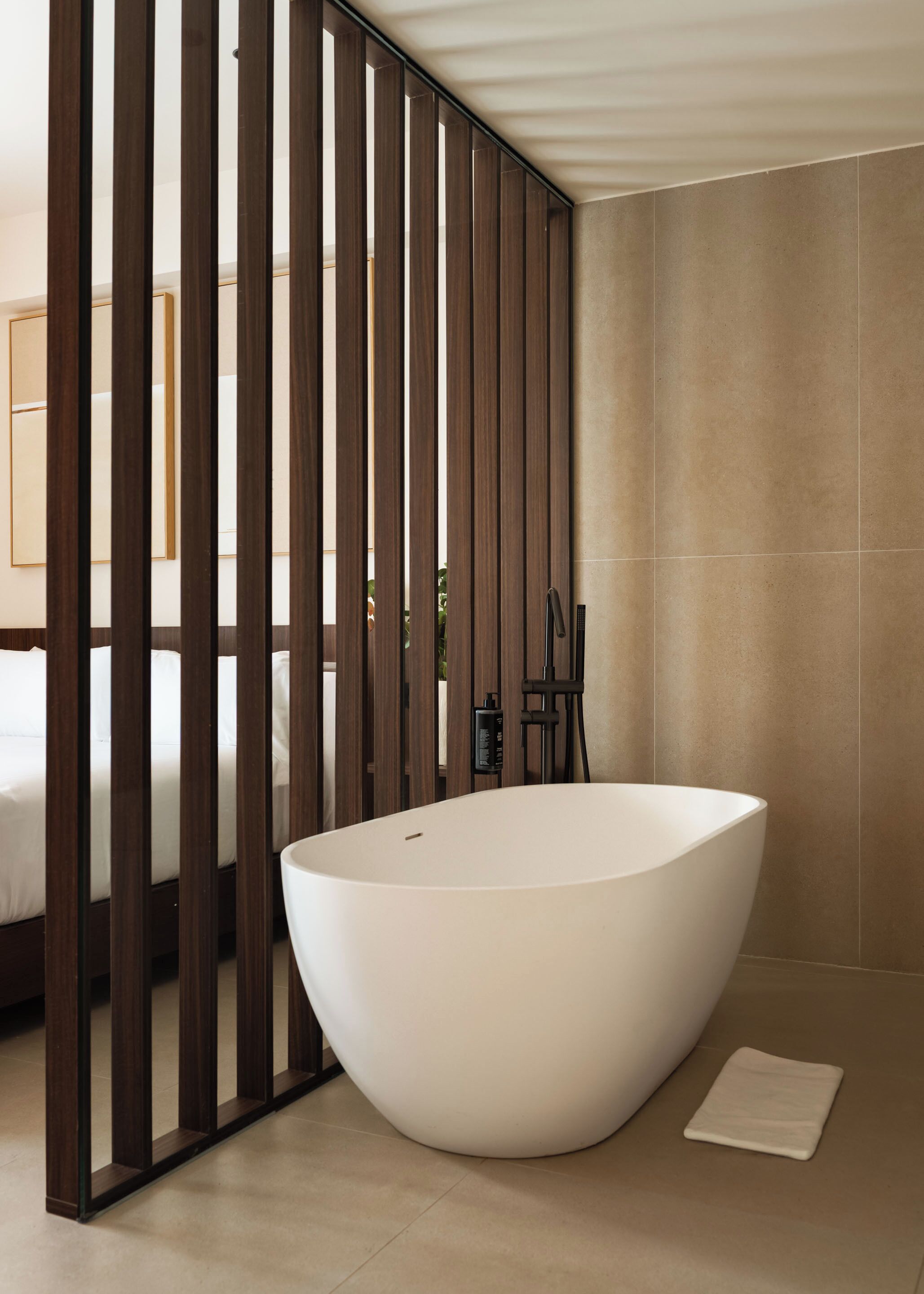 Un baño moderno con una bañera independiente, un separador de madera y suelo de baldosas.