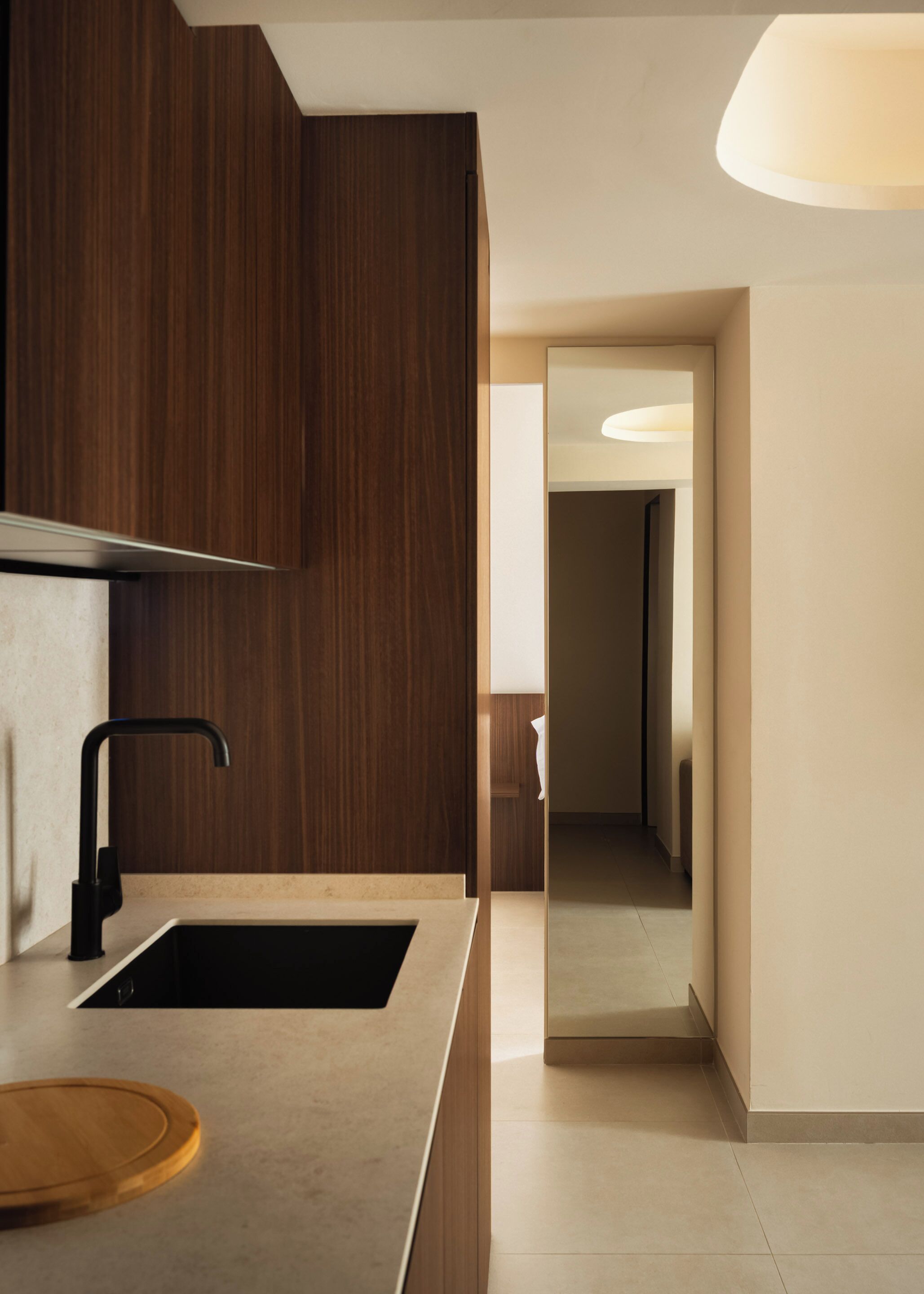 Une cuisine moderne avec des meubles de couleur bois foncé, un robinet noir et un plan de travail de couleur claire.