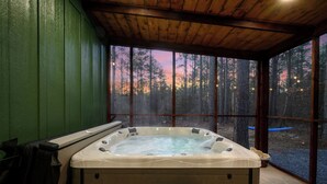 Ein Whirlpool in einem Raum mit großen Fenstern mit Blick auf einen Wald.