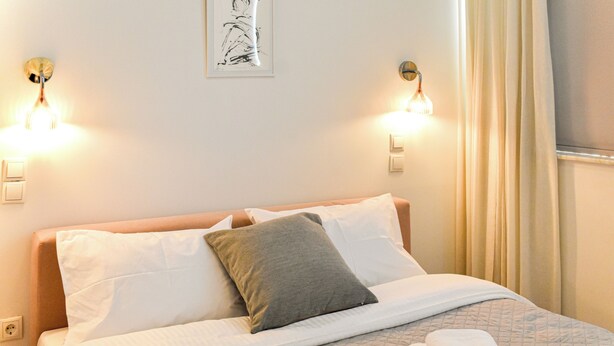 Un lit bien fait, recouvert d’une courtepointe matelassée, deux lampes de chevet et une œuvre d’art encadrée au mur.