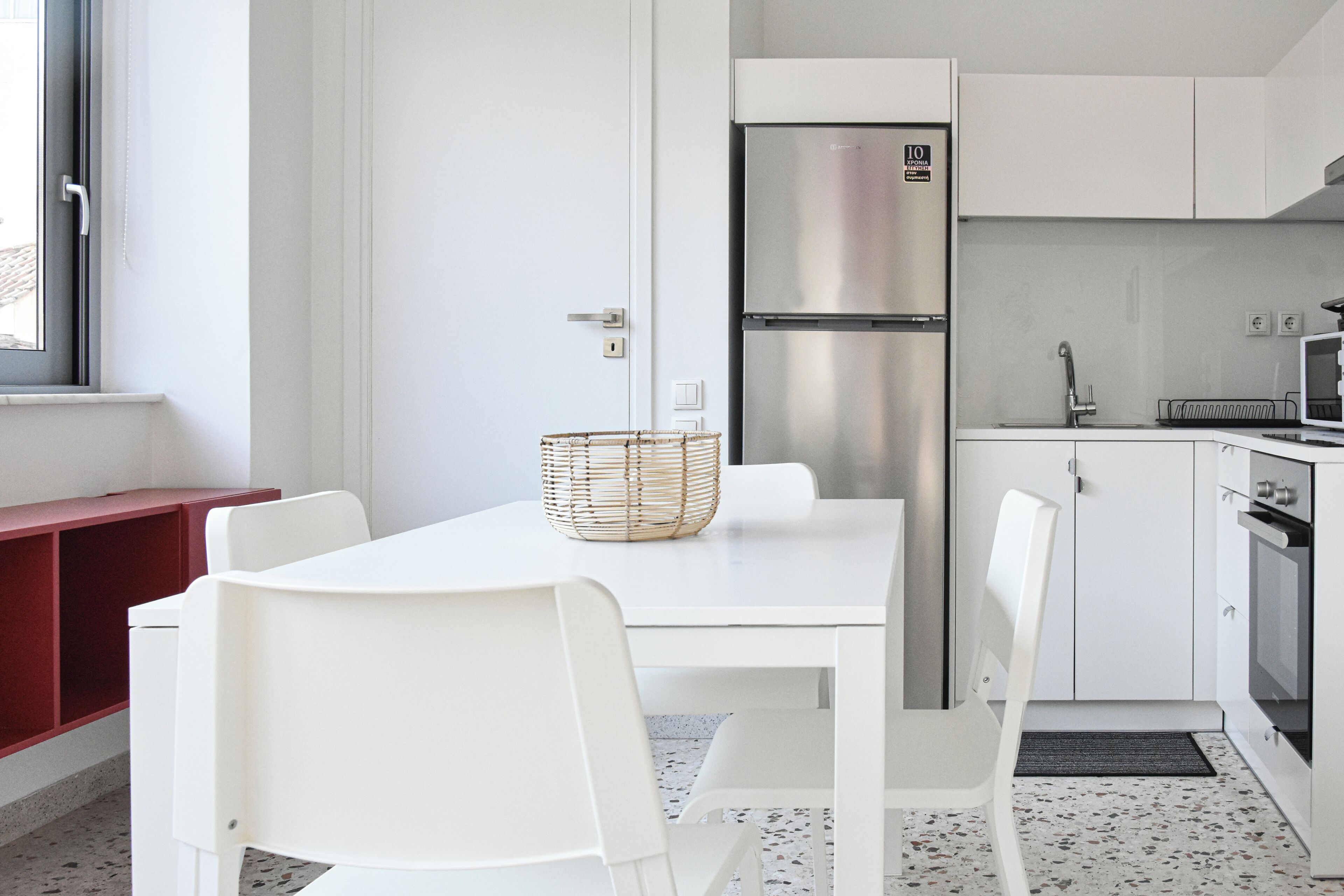 A modern kitchen with white cabinetry, a stainless steel refrigerator, and a microwave.