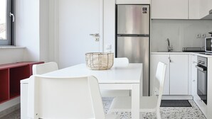 Une cuisine moderne avec des meubles blancs, un réfrigérateur en acier inoxydable et un four à micro-ondes.