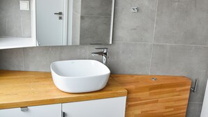 Une salle de bain moderne avec un lavabo blanc, un meuble-lavabo en bois et des toilettes blanches.