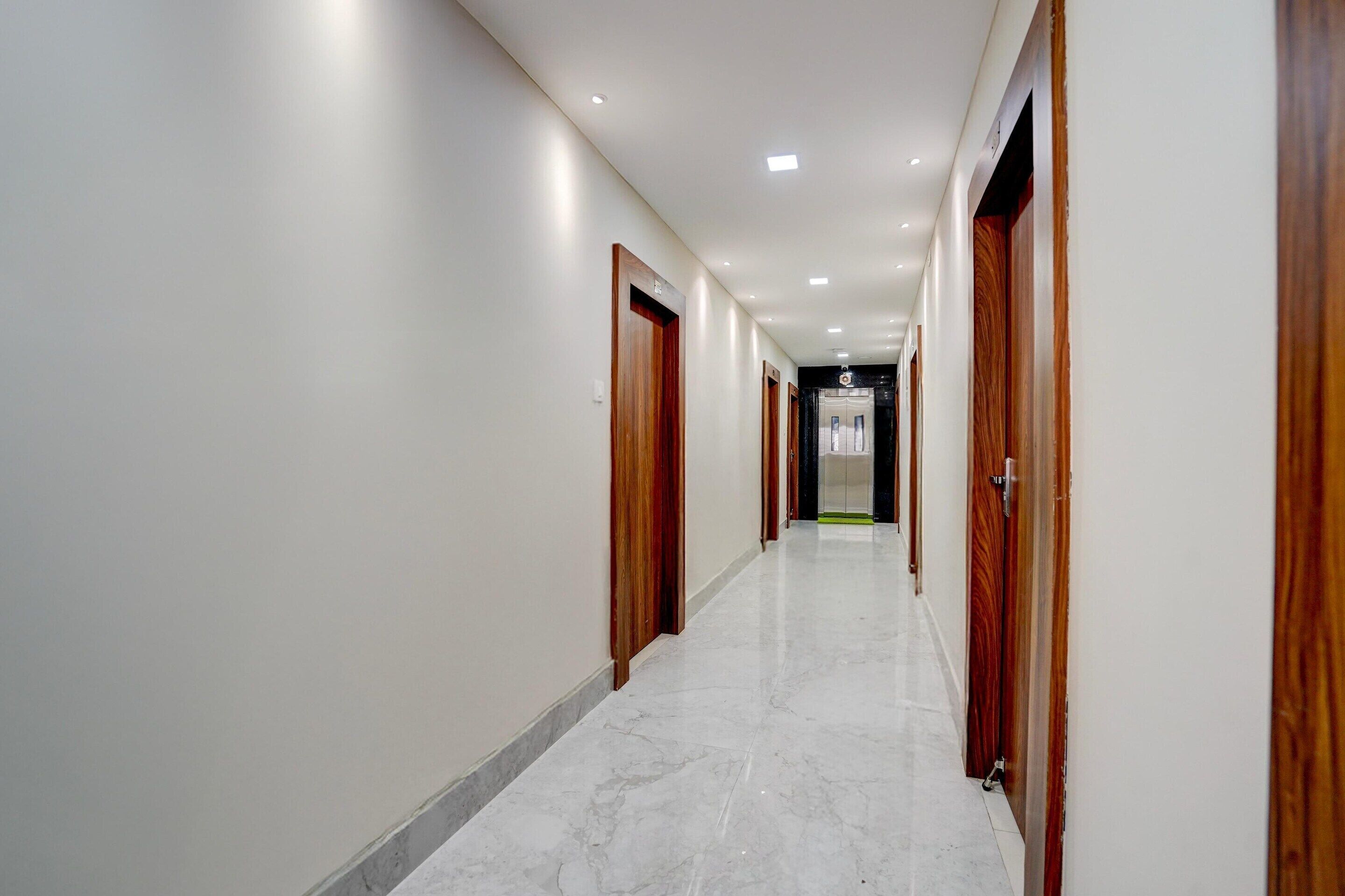 A long, narrow hallway with wooden doors on both sides and a marble floor.