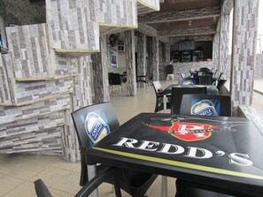 A restaurant interior with stone walls, tables with logos, and chairs. - Rocozee Hotel  (Warri)