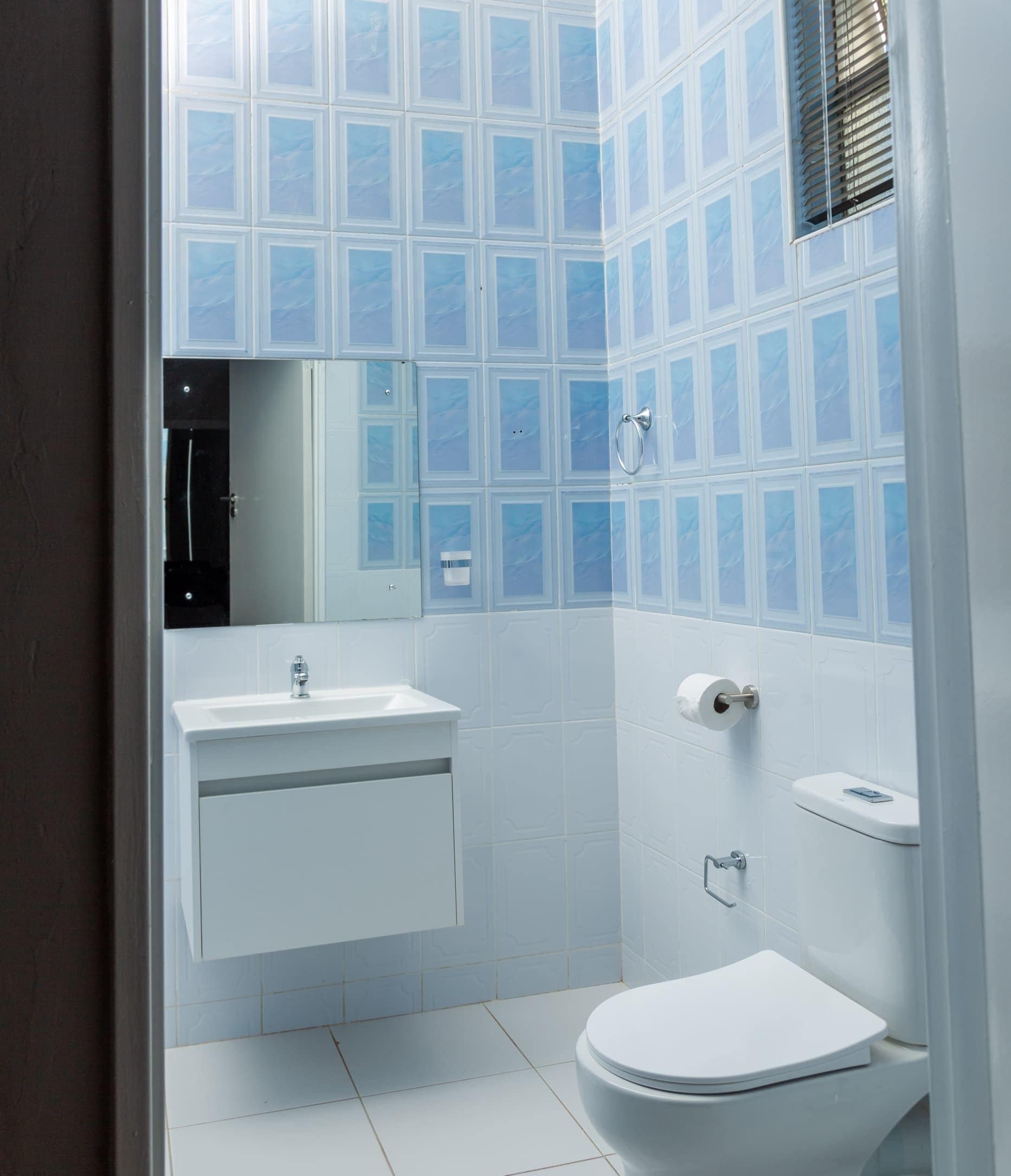 Ein Badezimmer mit weißem Waschbecken, Toilette und Spiegel.