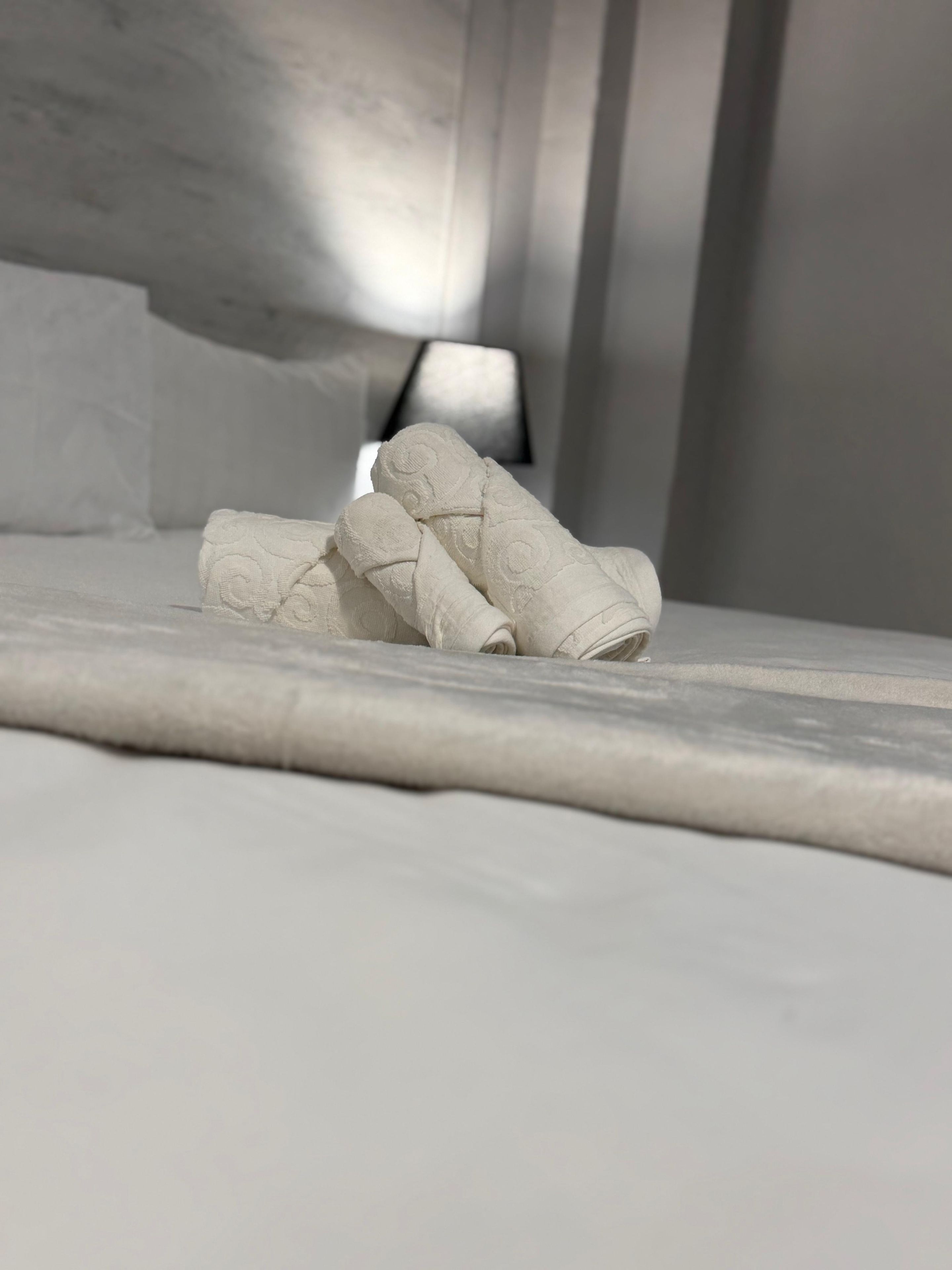 Una cama bien hecha con toallas blancas enrolladas.