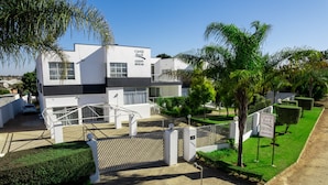 A modern guest house with a white facade, a gated entrance, and a well-maintained garden. - Castle Rock Guest House  (Bulawayo)