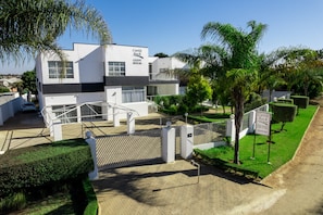 A modern guest house with a white facade, a gated entrance, and a well-maintained garden. - Castle Rock Guest House  (Bulawayo)