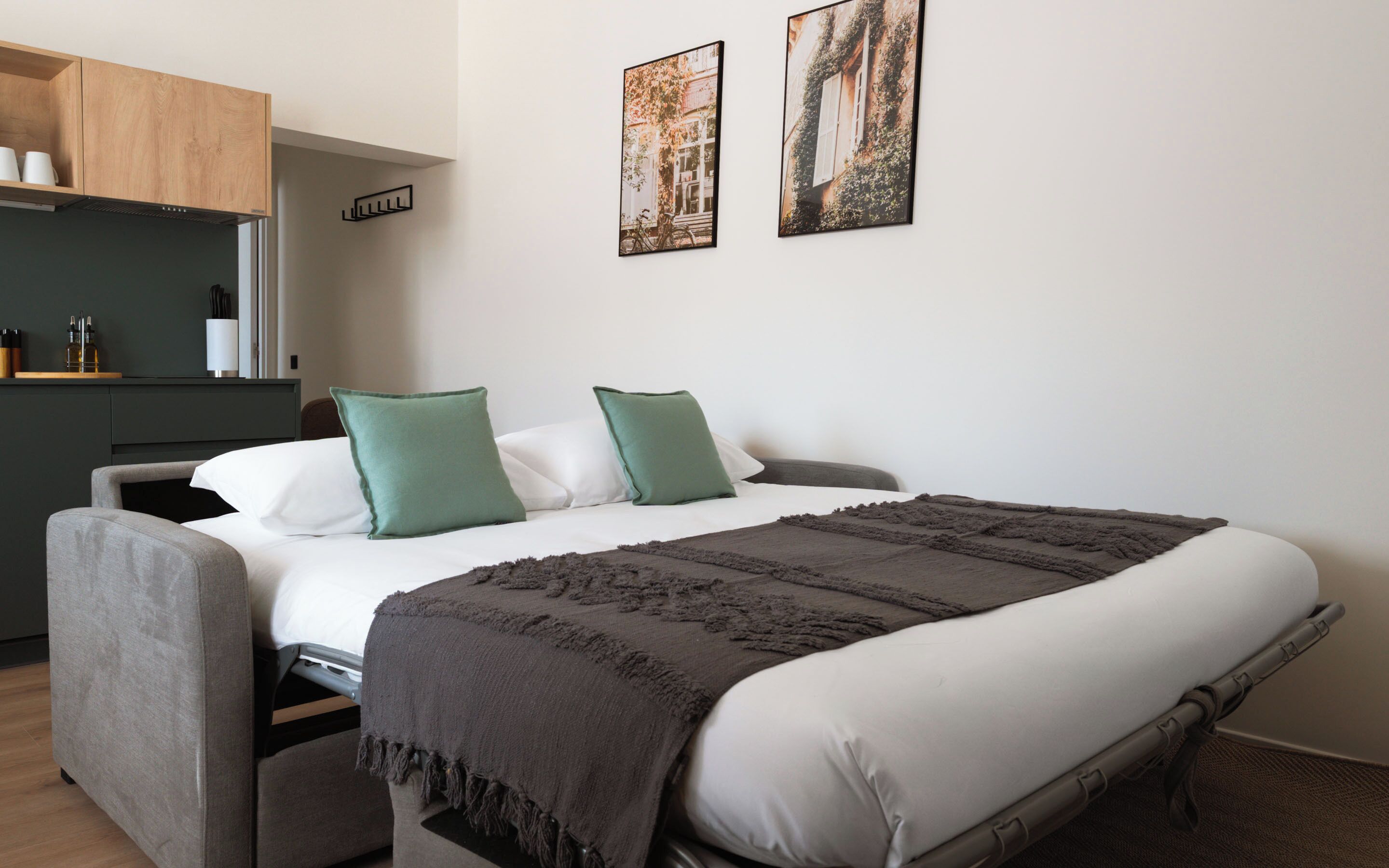 Un dormitorio con una cama, un escritorio y dos cuadros en la pared.
