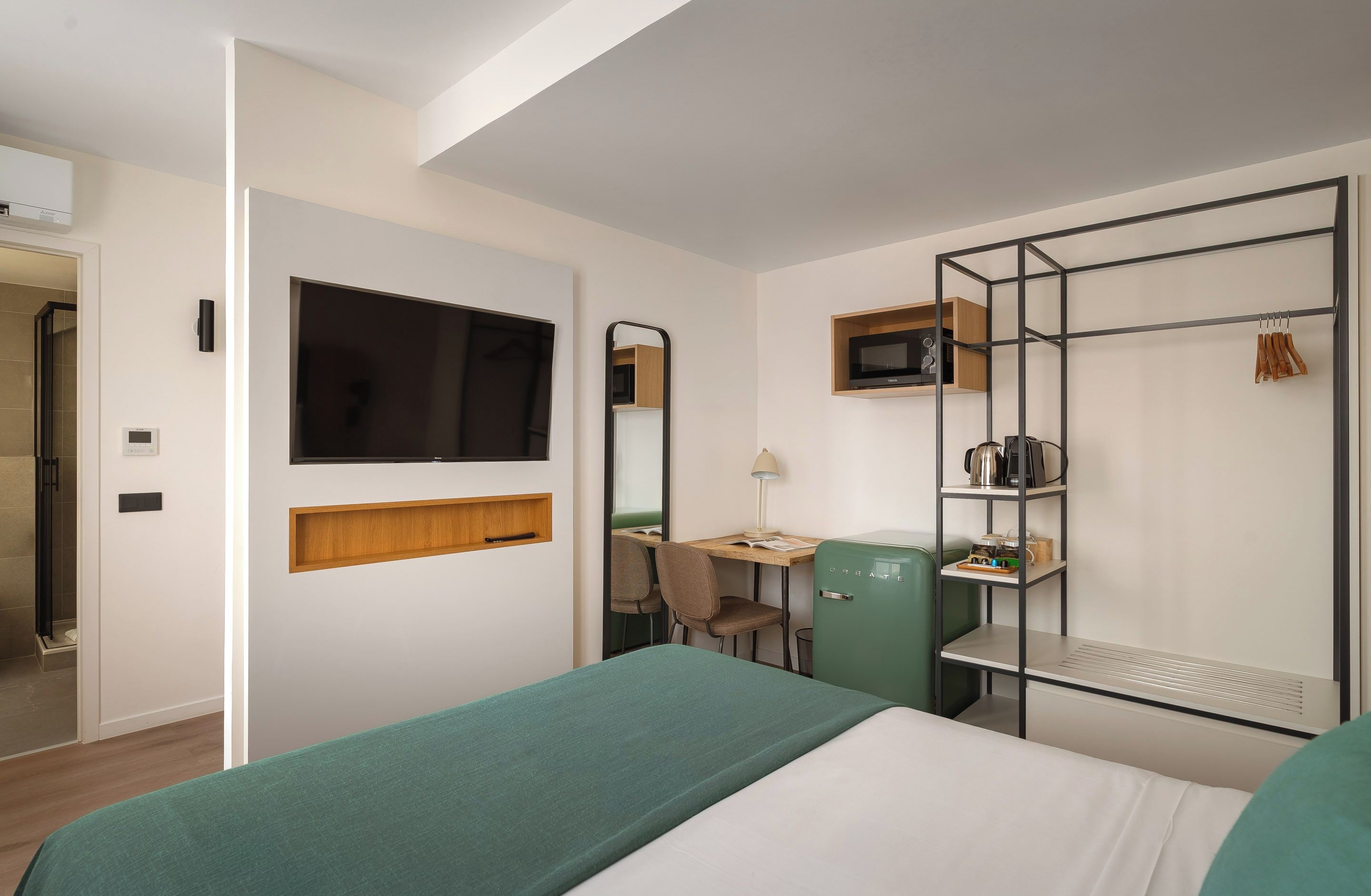 A hotel room with a bed, a desk with a chair, a television, a microwave, and a wardrobe.