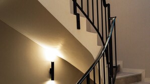 A spiral staircase with a handrail and a light fixture on the wall. - Limehome Versailles Rue du Bailliage (Versailles)