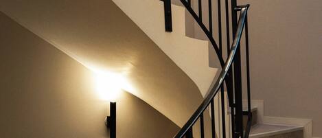 Eine Wendeltreppe mit Handlauf und einer Wandleuchte.