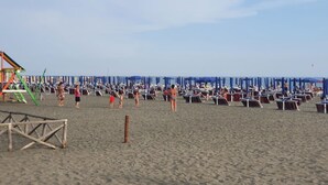 Een strand met rijen parasols en ligbedden, een uitkijktoren voor de badwachters en een zandstrand.