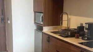 Una cocina compacta con armarios de madera, un microondas integrado y una cafetera.