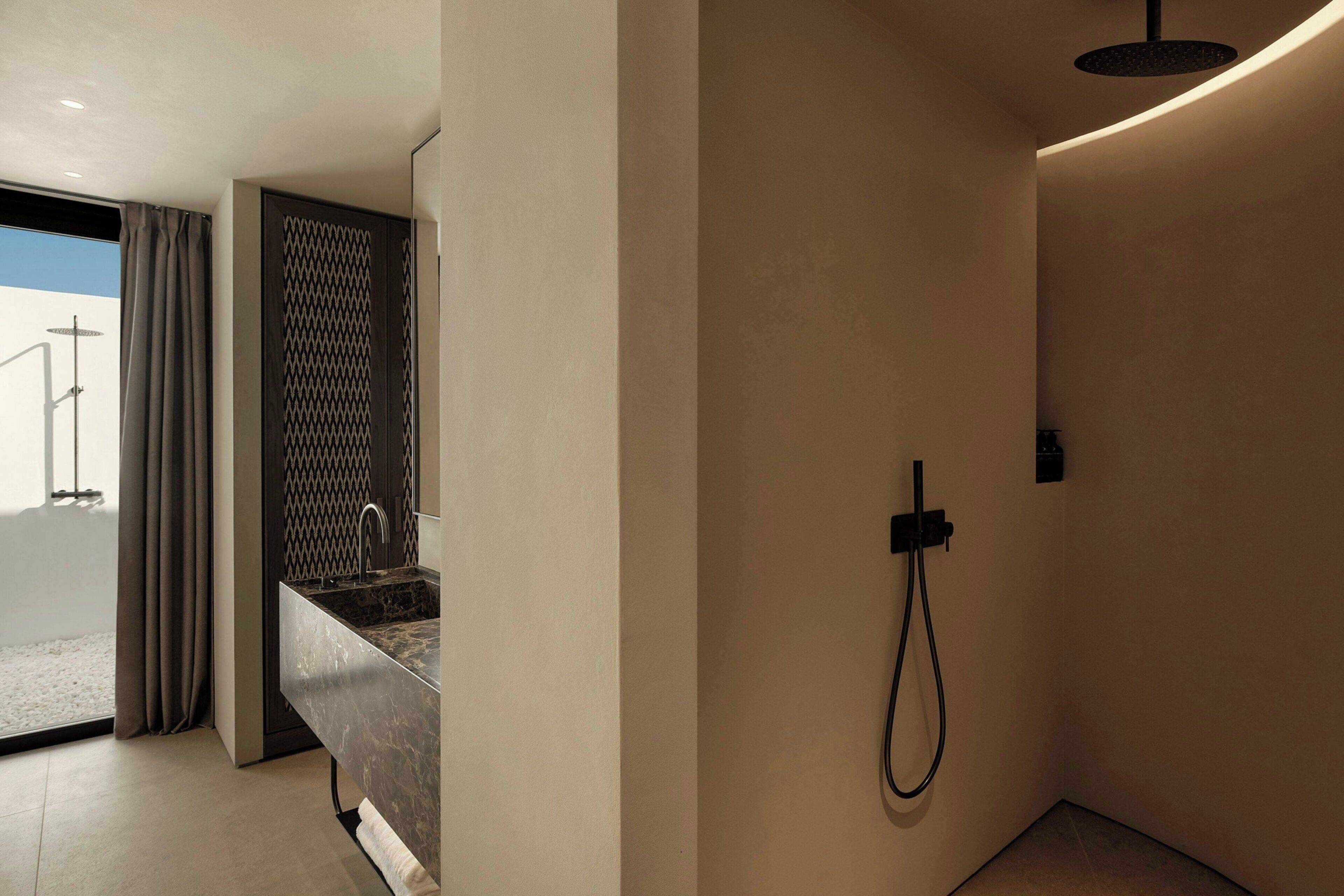Een moderne badkamer met een douche, wastafel en een glazen deur naar een balkon.