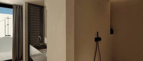 Een moderne badkamer met een douche, wastafel en een glazen deur naar een balkon.